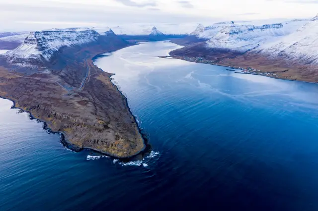 Aerial of a deep blue fjord ringed by snow-capped mountains, Iceland