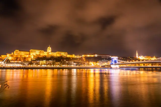 Buda Castle and the Chain Bridge glowing gold over the Danube at night.