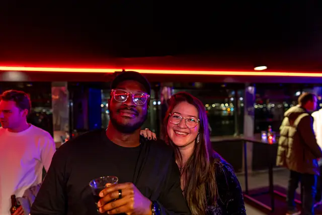 Two guests smiling over drinks at an evening event.