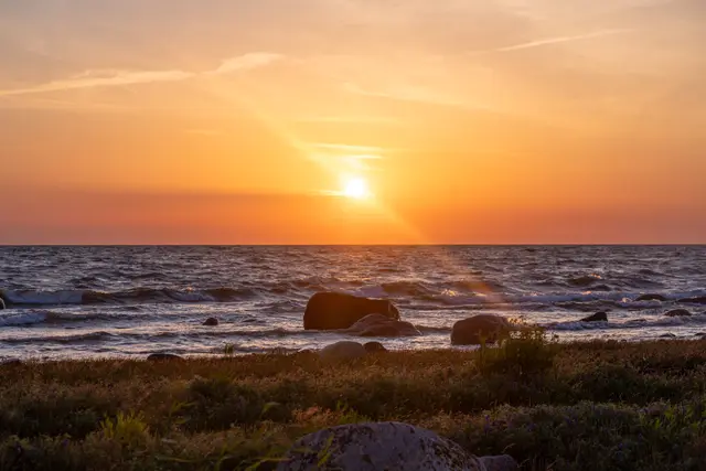 The sun setting over the Baltic Sea and rocks.