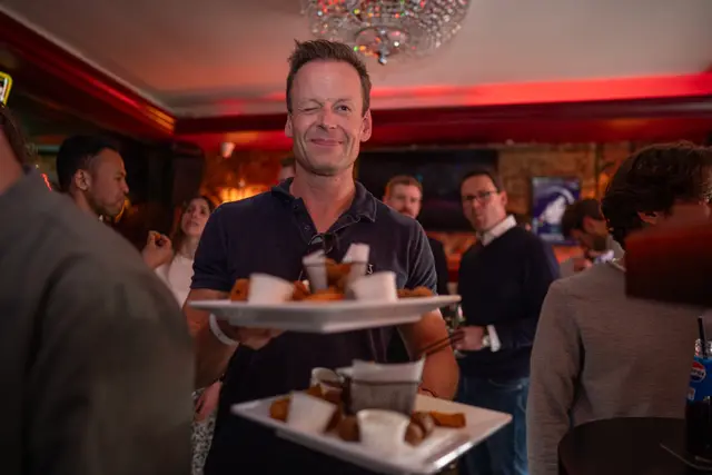 A server carrying a tray of refreshments at an event.