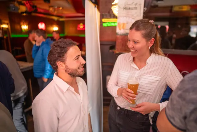 A man and woman chatting over drinks at an event.