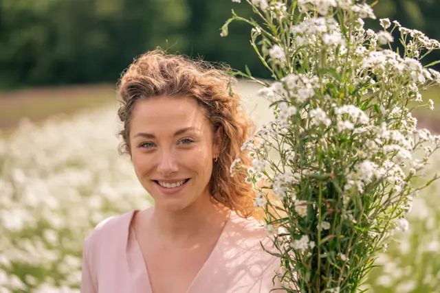 A smiling woman among white summer flowers.