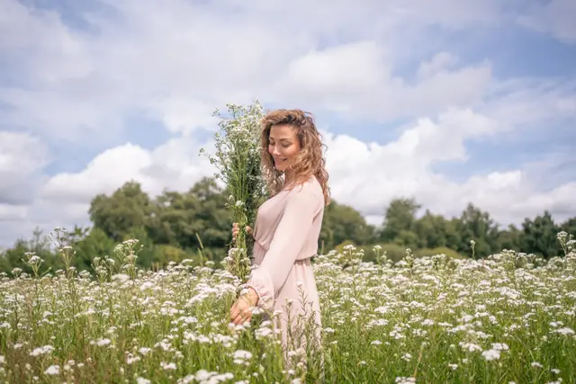 A woman in a flowing dress among daisies.