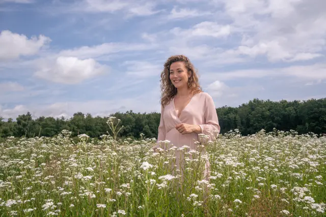 A woman standing in a field of daisies.